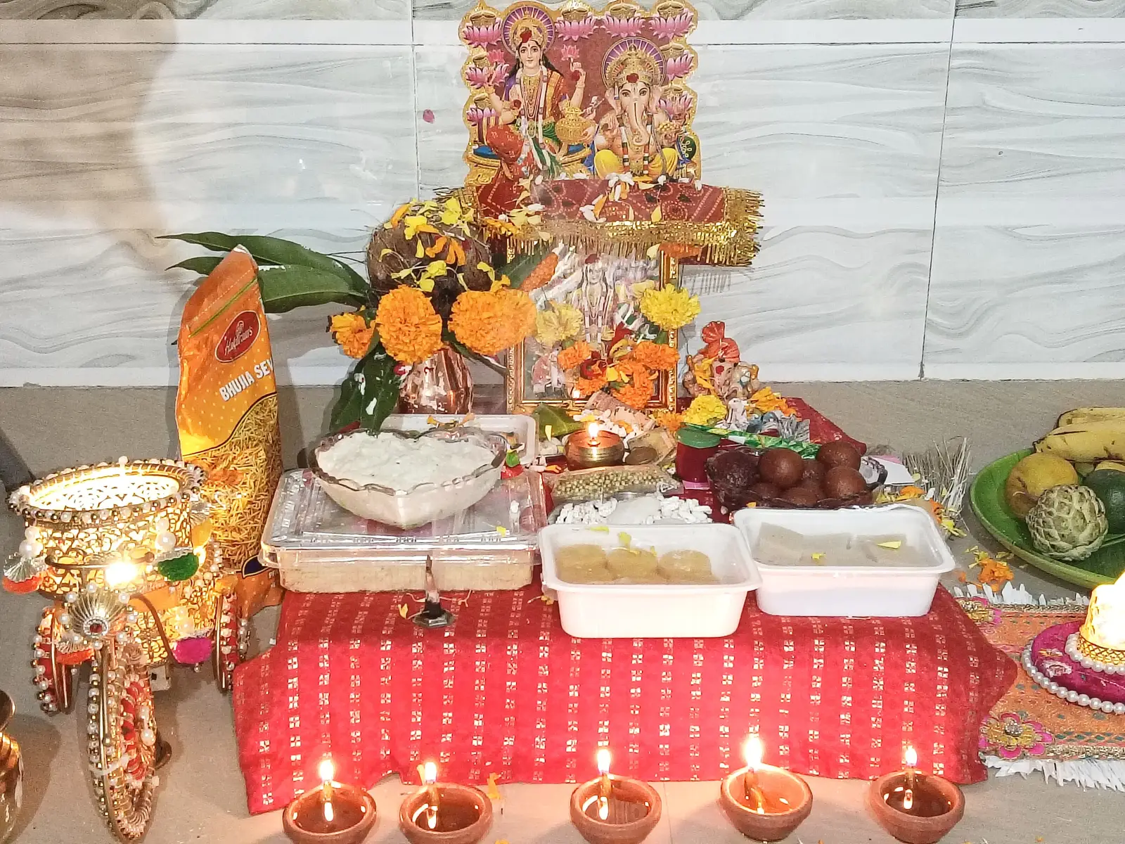 A traditional Lakshmi Puja thali with diyas, flowers, and rangoli set up for Diwali.
