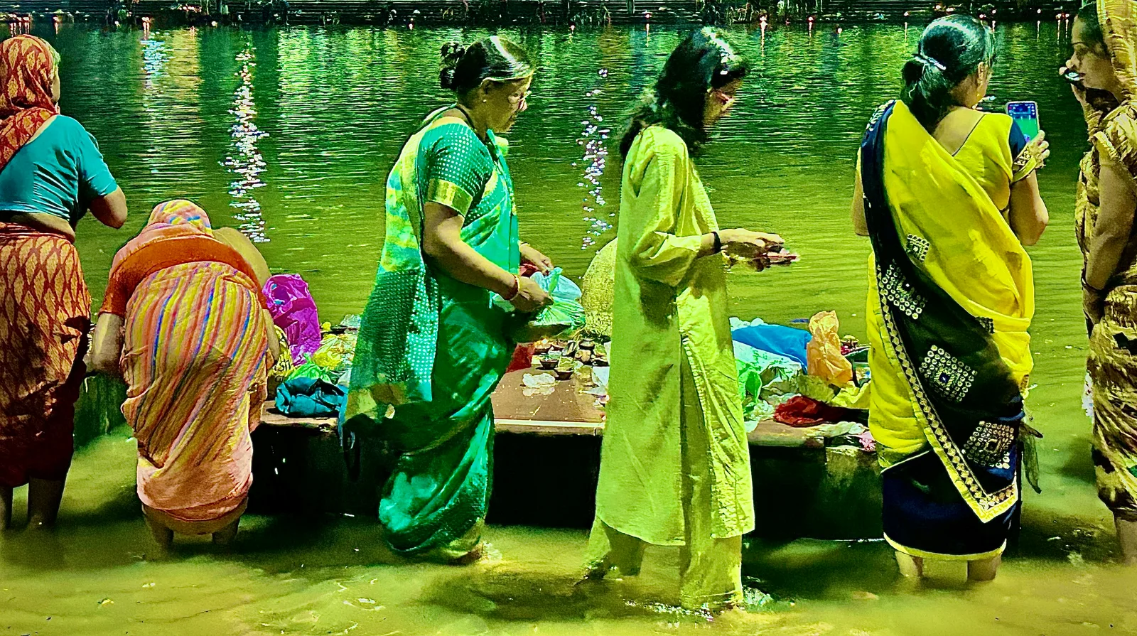 Women making offerings at the water's edge at Ram Ghat on the Kshipra river, Ujjain, during Pitru Paksha.