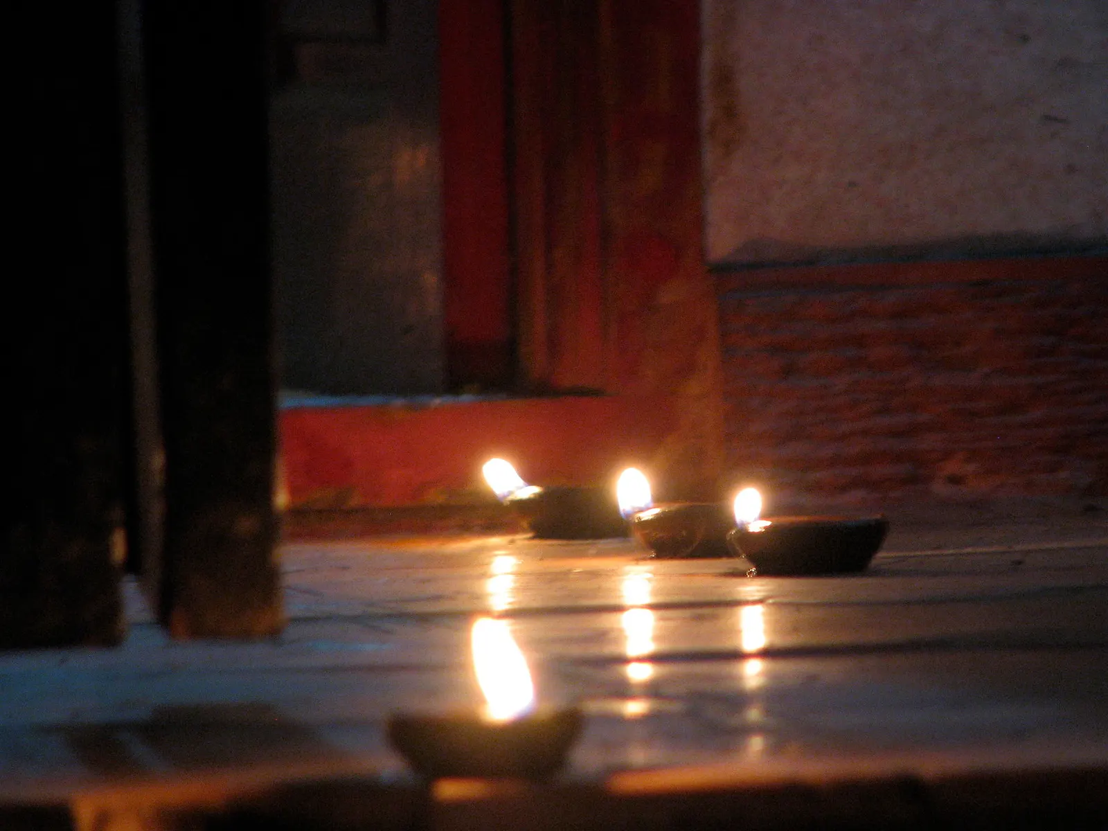 A single lit diya on a windowsill at dusk.