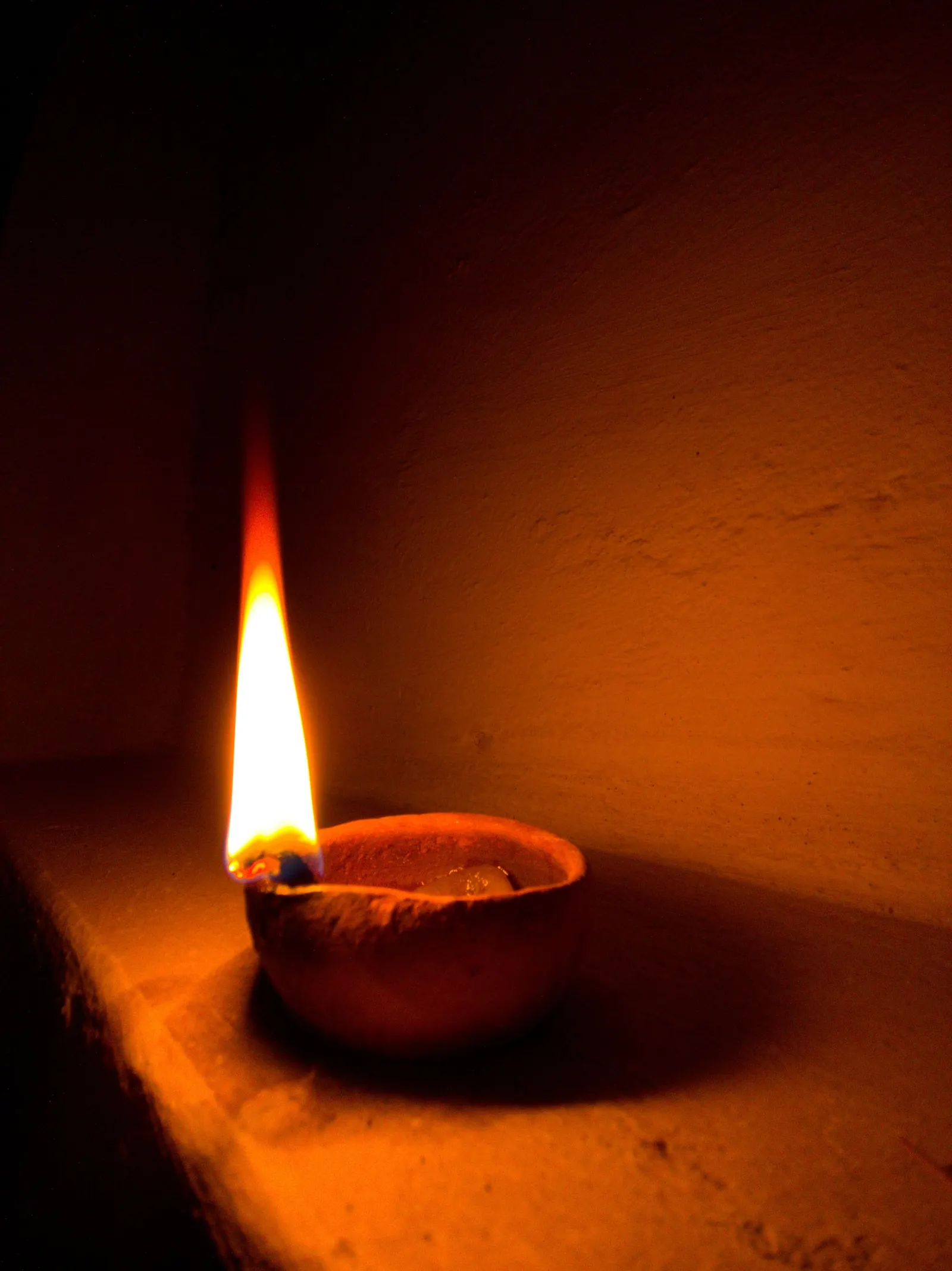 A single lit oil lamp glowing quietly in a dim room.