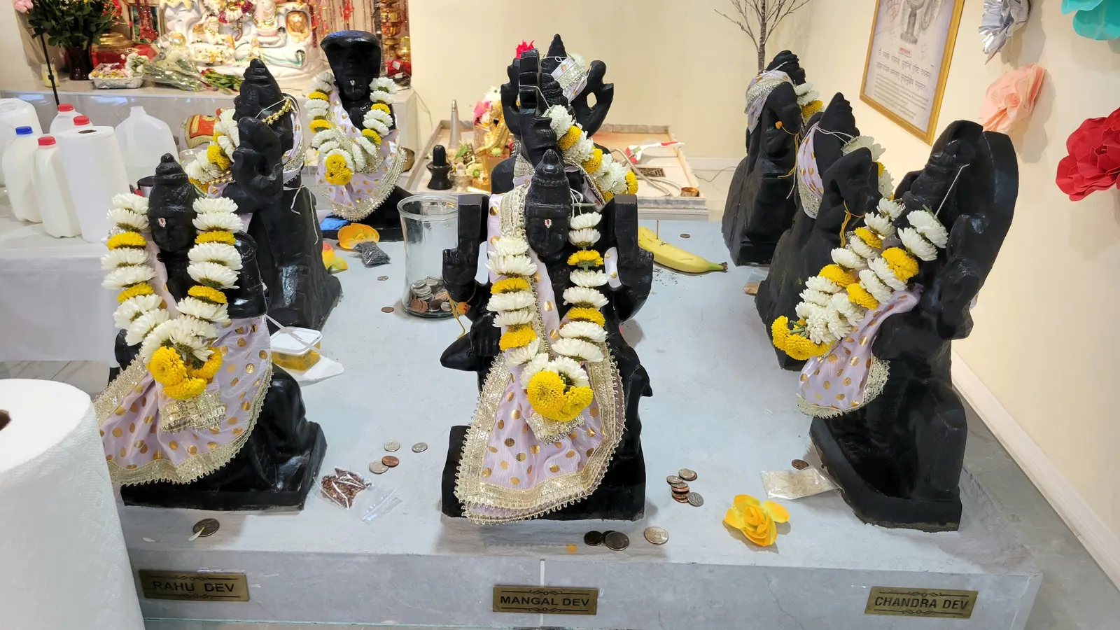 Nine planetary deity idols arranged in a traditional Navgraha temple mandapam.