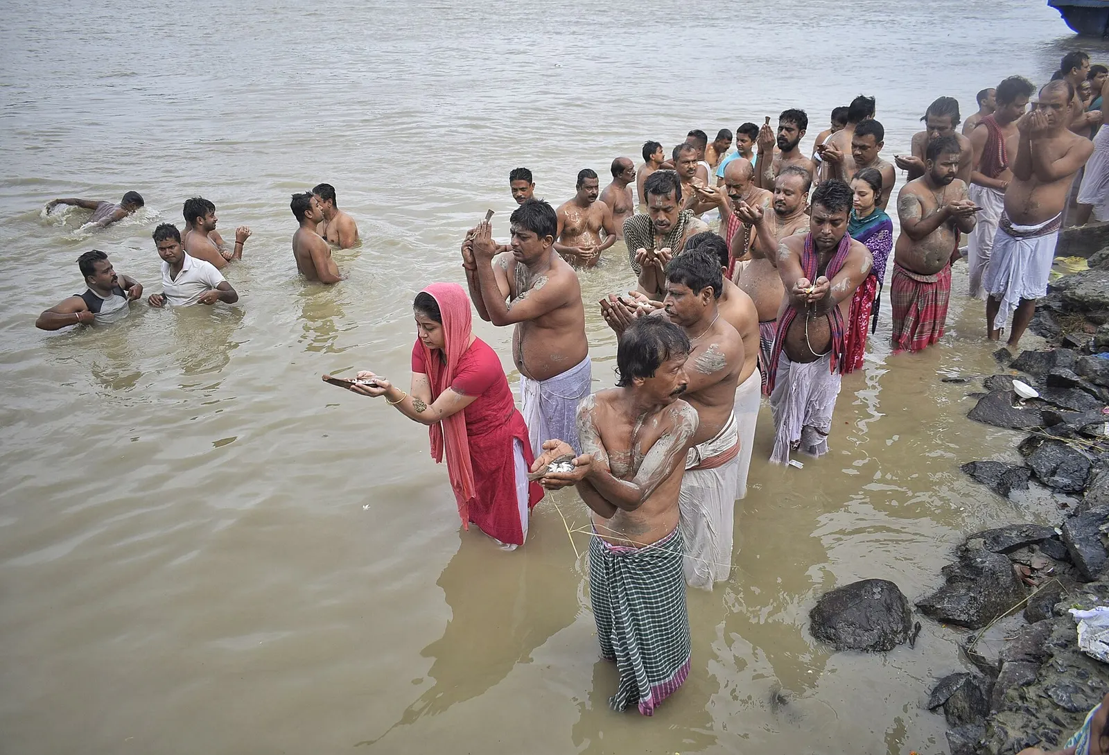 Hands offering water during a riverside ritual at sunrise.