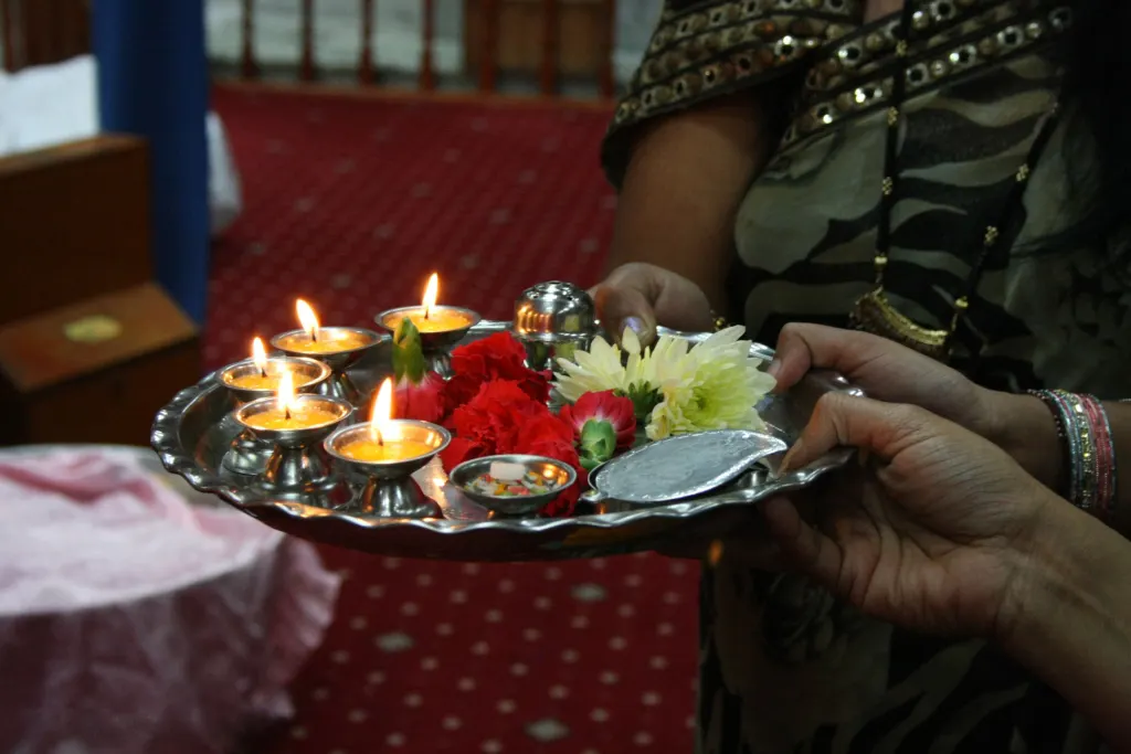 A traditional puja thali arranged with a diya and offerings.