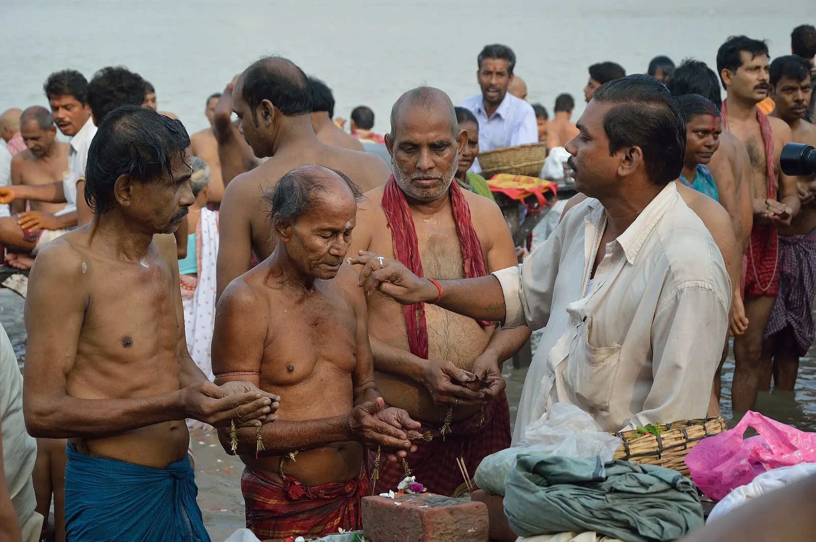 Close-up of hands pouring water in a riverside ritual offering.