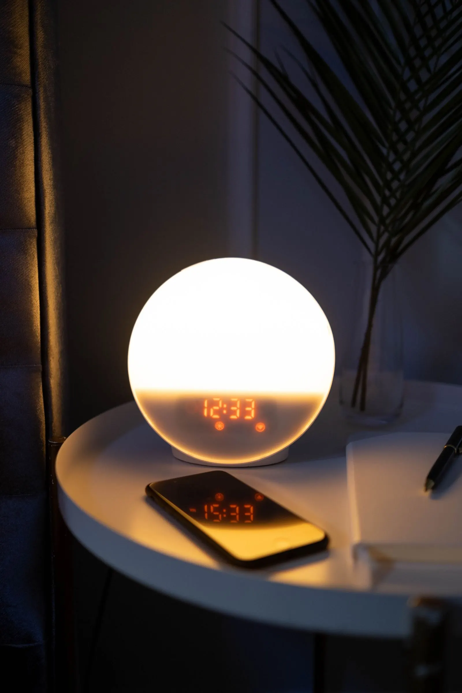 A phone alarm glowing on a nightstand in a dark bedroom.